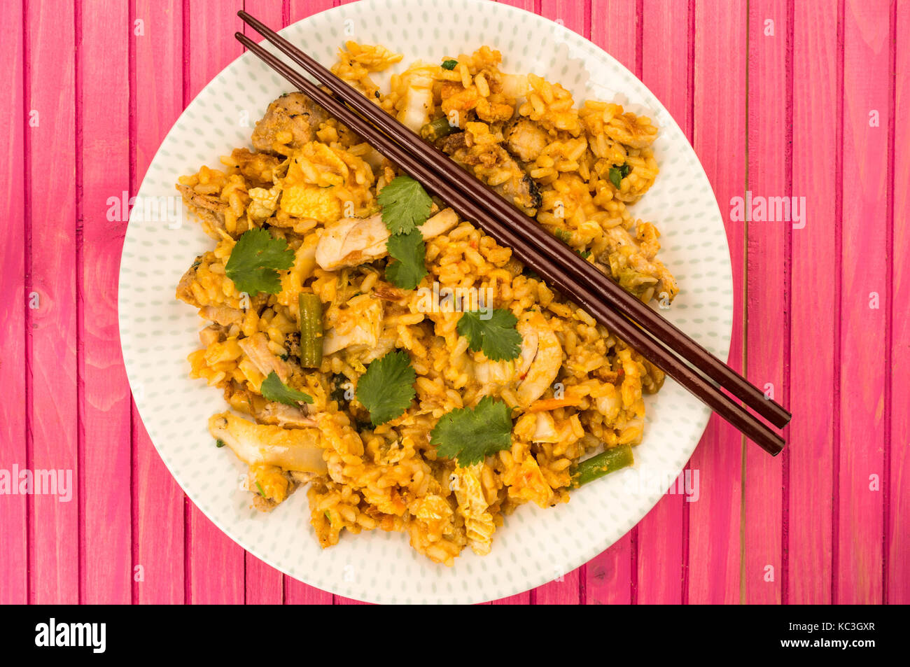 Huhn Nasi Goreng Indonesisch essen gegen einen hölzernen rosa Hintergrund Stockfoto