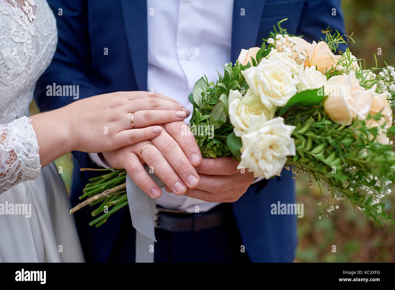 Braut legte ihre Hand auf der Bräutigam die Hand mit dem brautstrauß Stockfoto