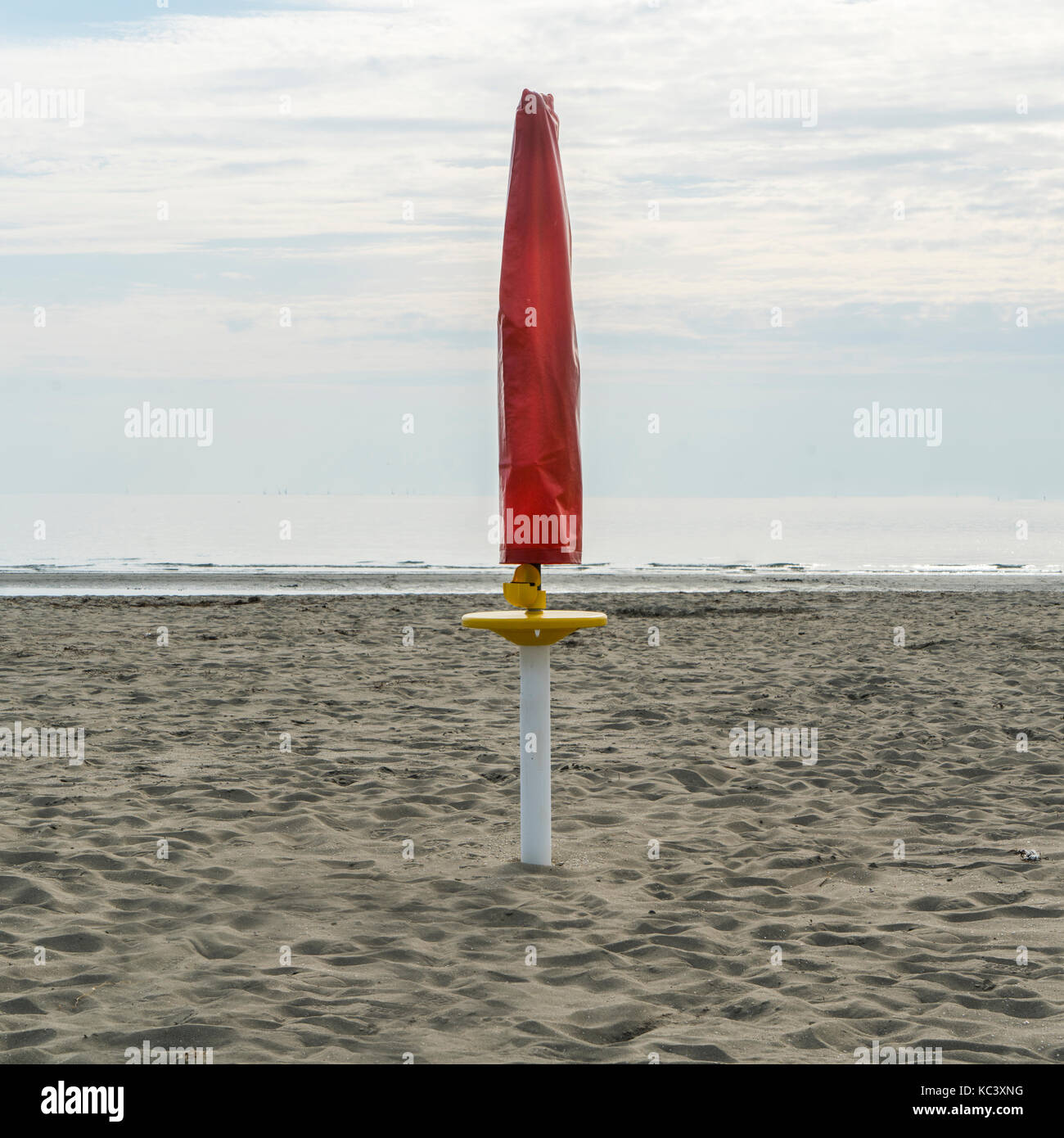 Ein Regenschirm geschlossen am Strand am Ende des Sommers Stockfoto
