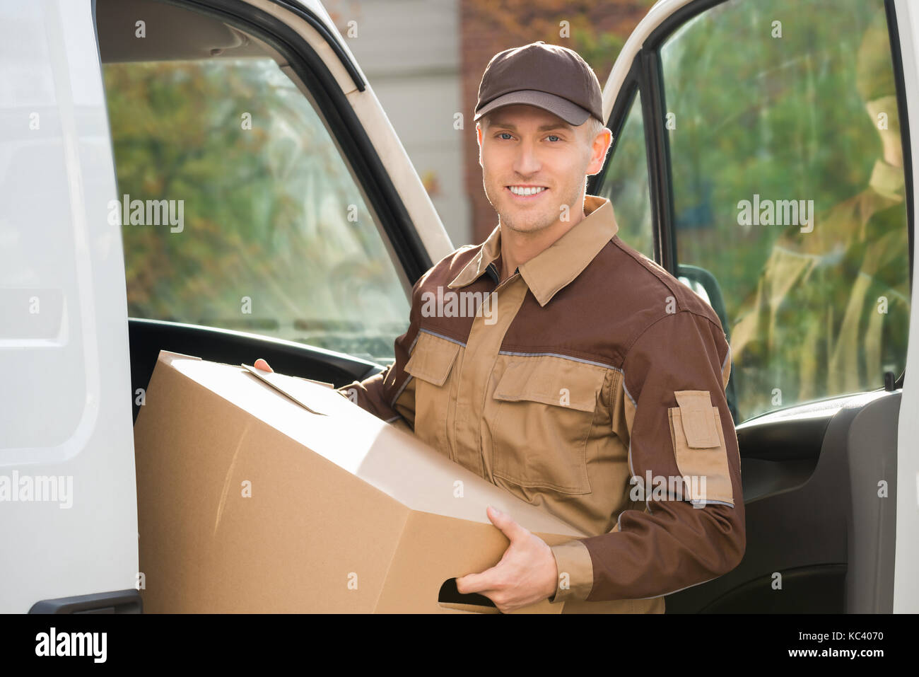 Porträt der jungen Delivery Man entfernen Karton vom Lkw Stockfoto