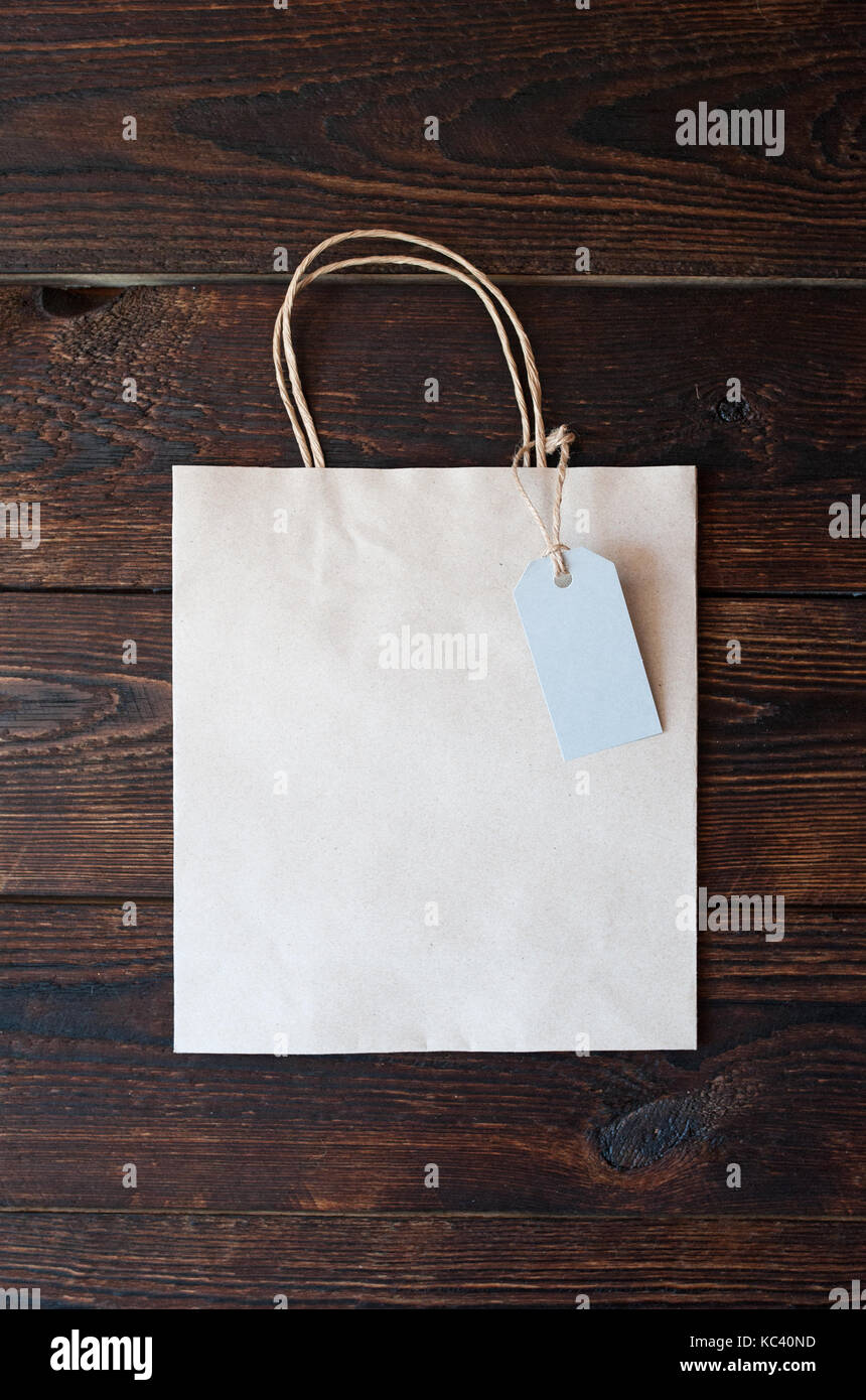 Mockup Papiertüte aus Kraftpapier mit Geschenkanhänger auf einer hölzernen Hintergrund Stockfoto