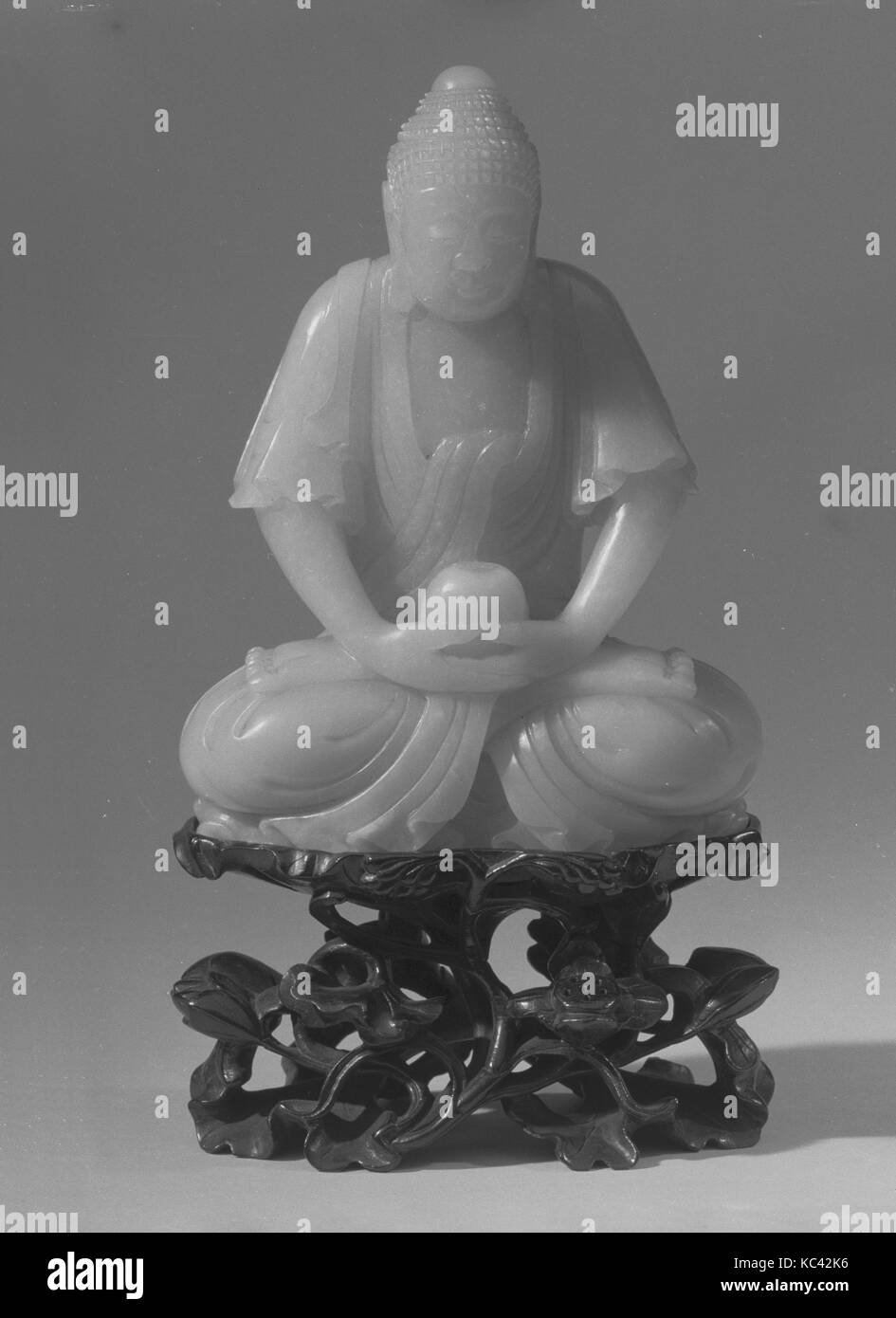 Sitzender Buddha, 18. Jahrhundert, China, Jade, H.5 11/16 in. (14,4 cm); H. (mit Ständer) 7 15/16 in. (20,2 cm); W. 4 1/2 in. (11.4 Stockfoto