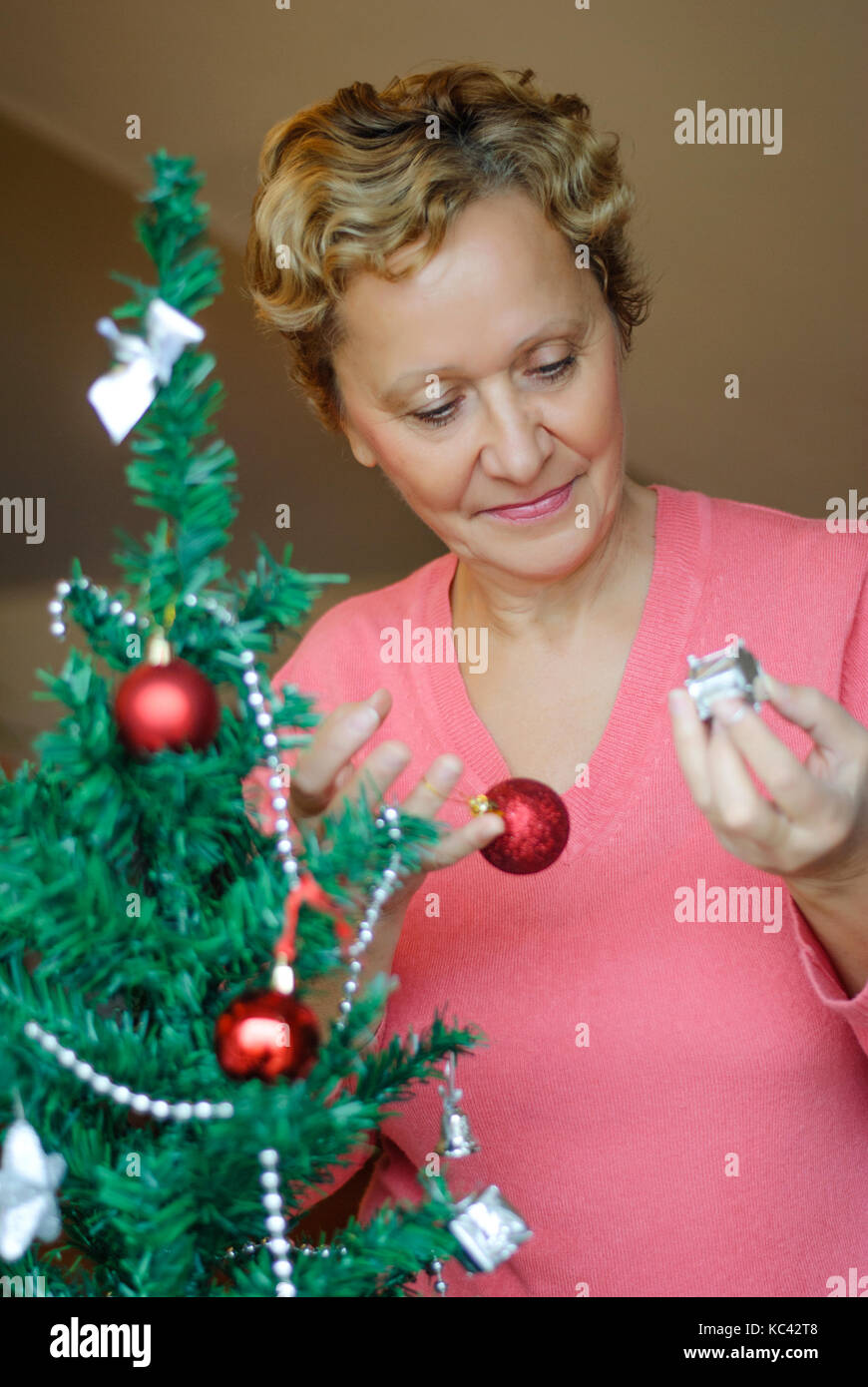 Schöne blonde Frau schmücken einen Weihnachtsbaum. Stockfoto