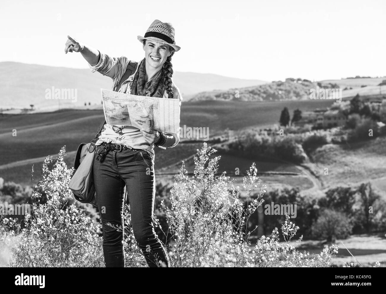 Entdecken Sie magische Ausblicke der Toskana. glückliche junge Frau Wanderer mit Tasche auf der Toskana Wanderung mit Karte und zeigen Stockfoto