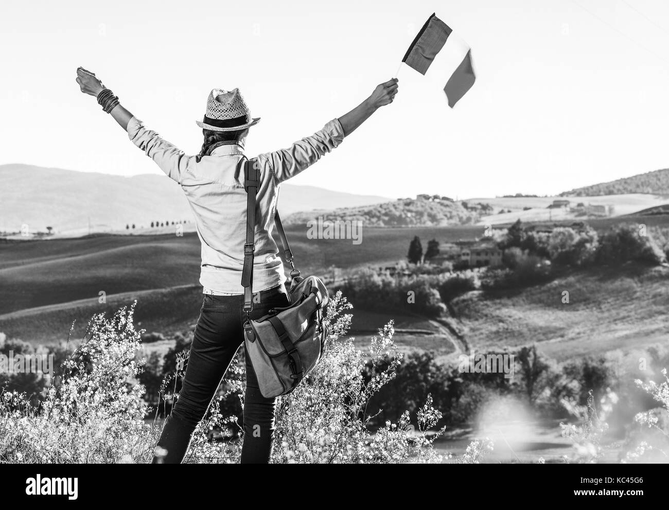 Entdecken Sie magische Ausblicke der Toskana. Hinter der jungen Frau Wanderer mit Tasche auf der Toskana Wanderung mit italienischer Flagge gesehen Freude Stockfoto