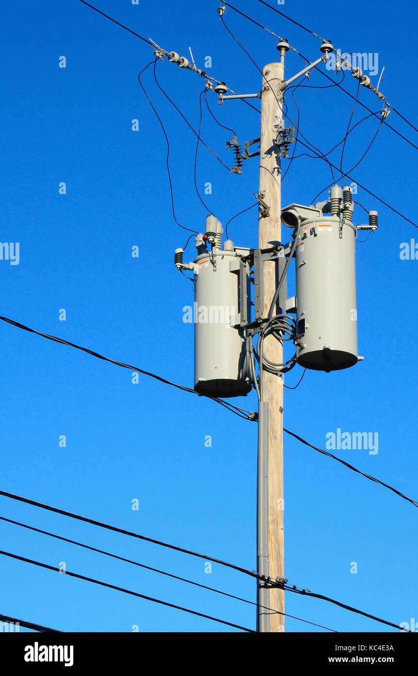 Zwei elektrische Transformatoren auf einer Stange mit vielen Drähte und Kabel mit einem tiefblauen Himmel Hintergrund. Stockfoto