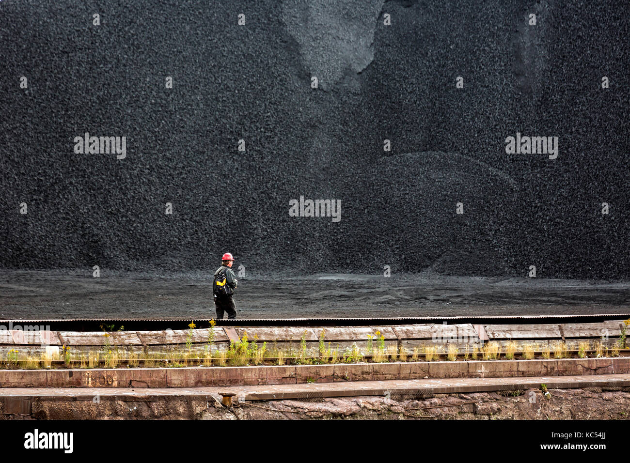 Sault Ste. Marie, Ontario, Kanada - ein Arbeitnehmer Spaziergänge Vergangenheit einen Haufen Kohle am Algoma Steel Mühle am Ufer des St. Mary's River. Stockfoto