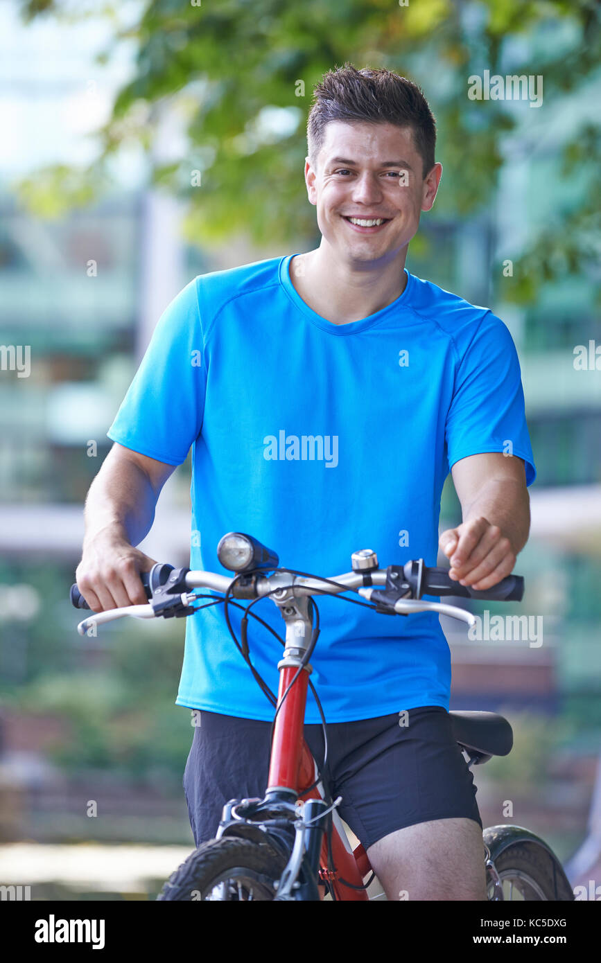 Portrait des jungen Mannes Radfahren am Fluss in städtischen Einstellung Stockfoto