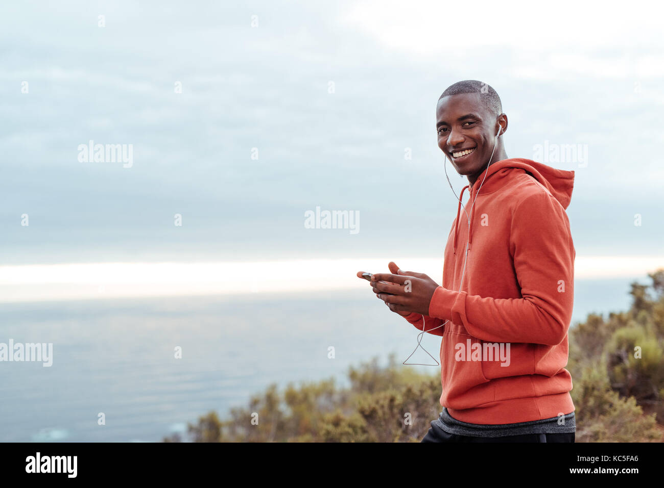 Lächelnd afrikanischer Mann Musik hören vor einem Lauf Stockfoto