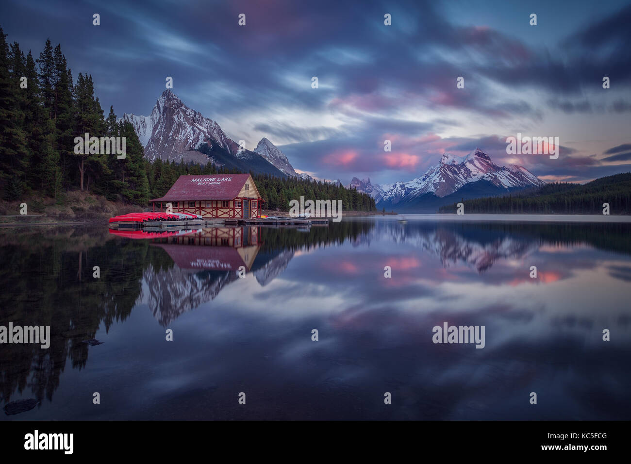 Haus und Boote in Maligne Lake, nach Sonnenuntergang. Feder an der Kanadischen Rockies. Kanada Landschaft. Spiegelbild. Stockfoto