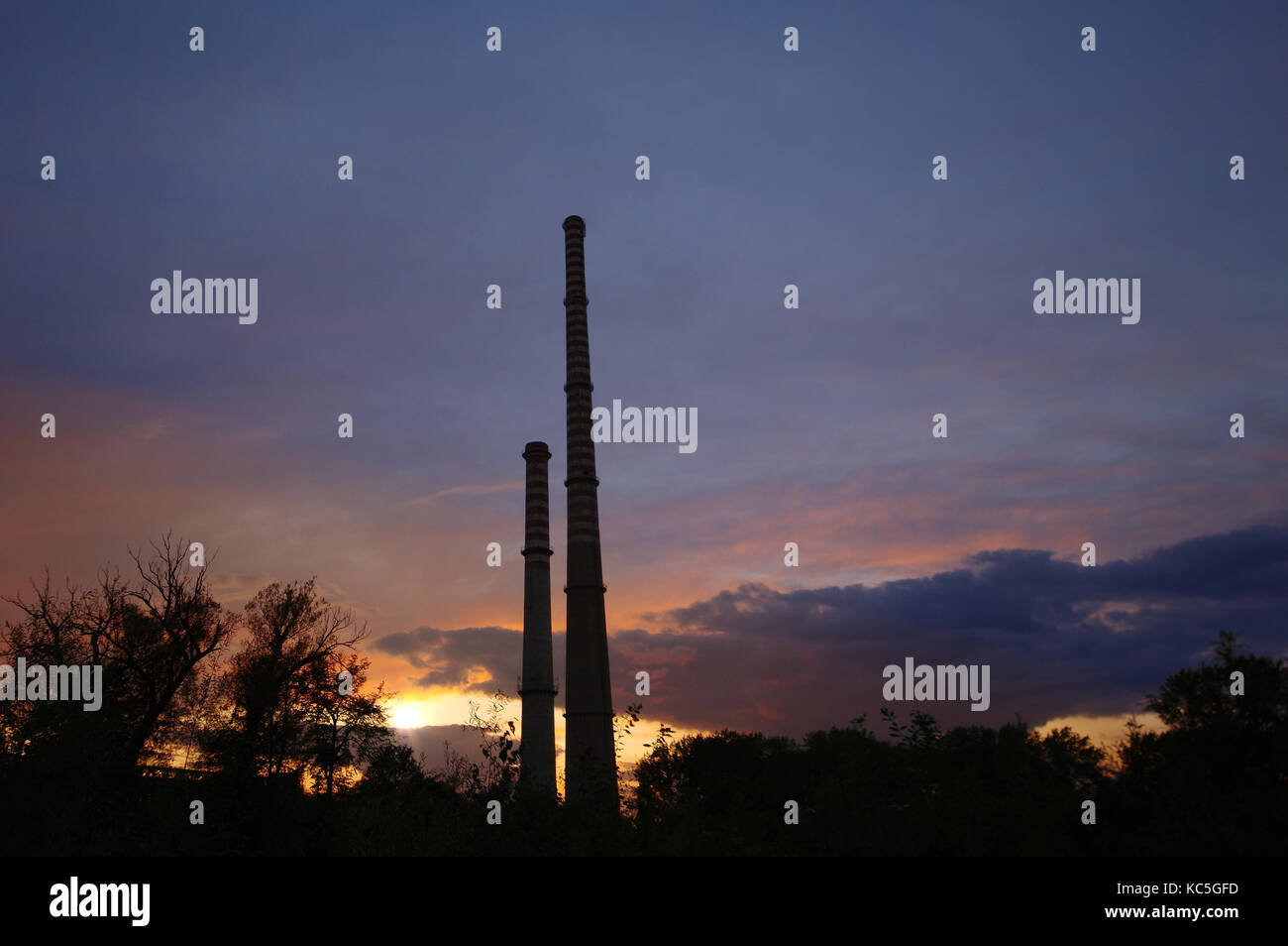 Alte Beton hohe Schornsteine an bewölkten Sonnenuntergang Himmel. Ursache der globalen Erwärmung. Stockfoto