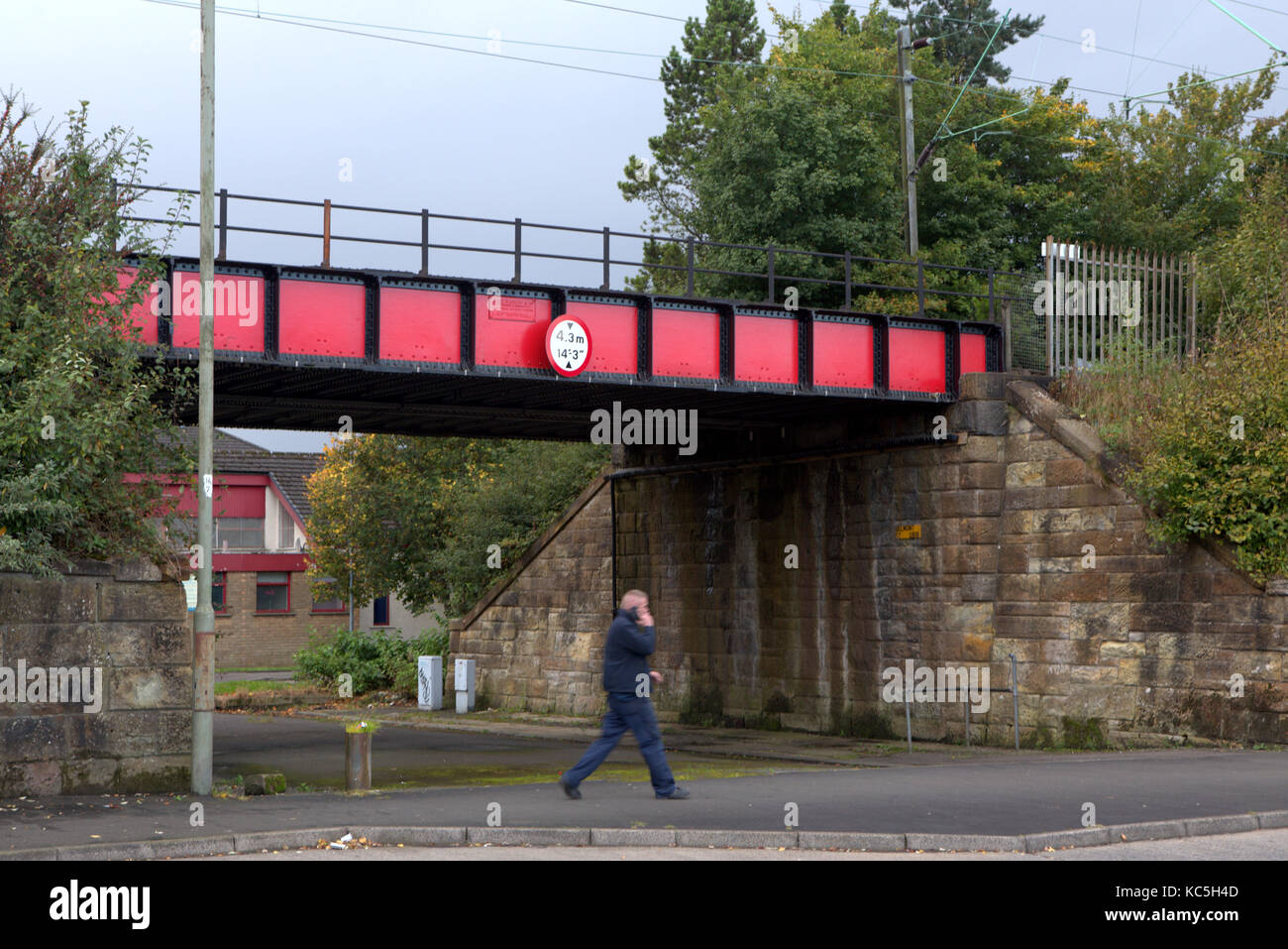 Mann auf dem Mobiltelefon in der Nähe von Bridge zu Fuß auf der Straße Kreuzung Straße Clydebank, Vereinigtes Königreich Stockfoto