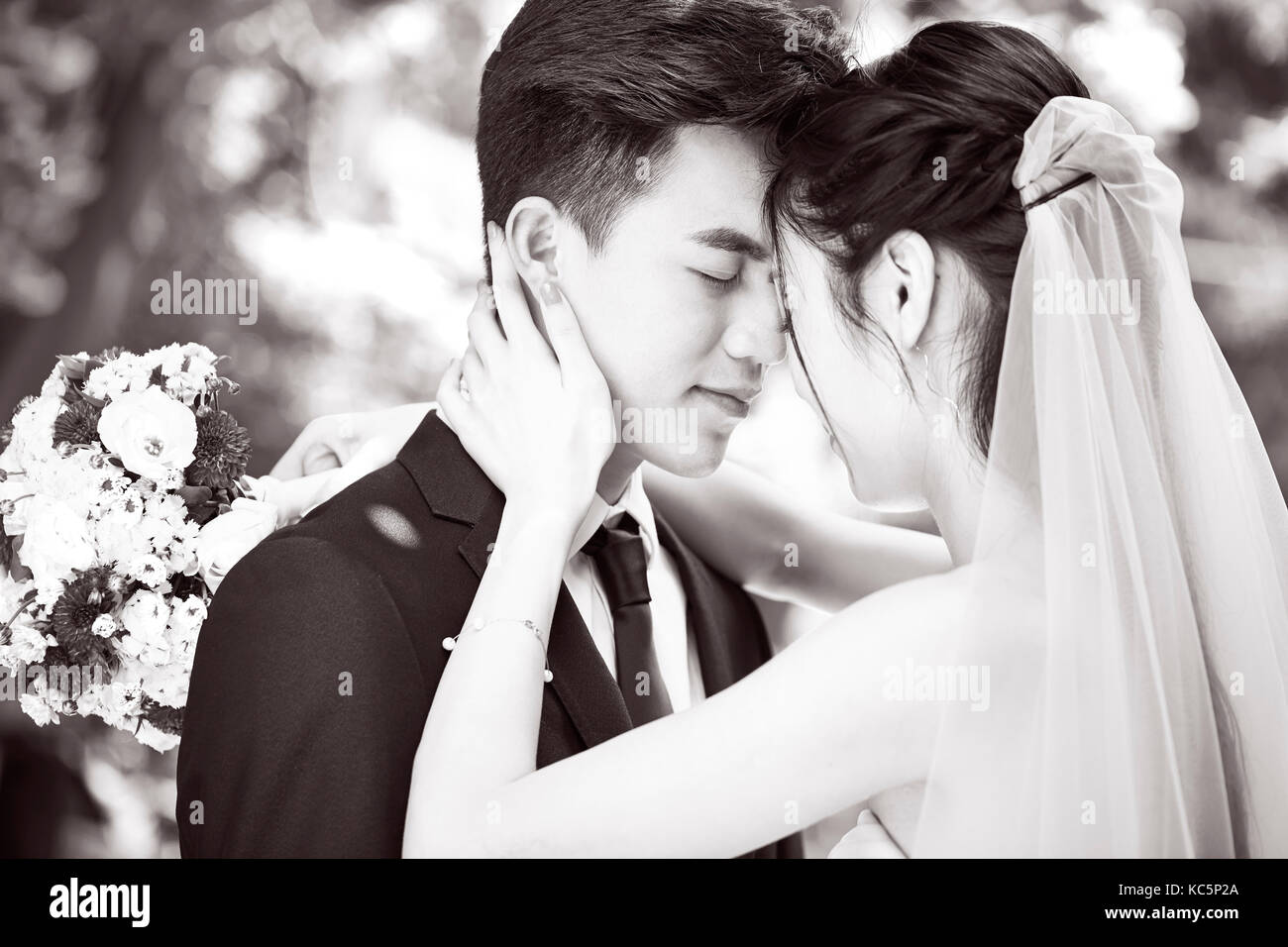 Junge asiatische Braut und Bräutigam küssen bei Trauung, Schwarz und Weiß. Stockfoto