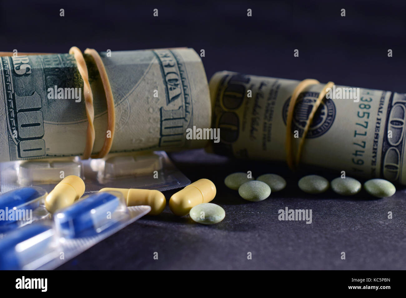 Geld Rollen und verschreibungspflichtigen Medikamenten auf dunklen Tisch. Stockfoto