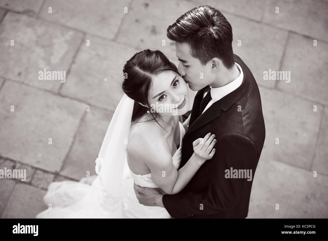 Junge asiatische Braut und Bräutigam umarmen Küssen tanzen in Open Air, Hohe Betrachtungswinkel, Schwarz und Weiß. Stockfoto