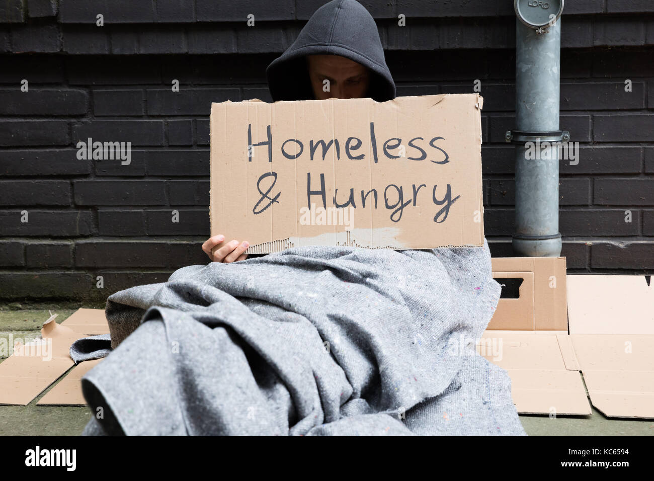 Obdachlose und Hungrige Menschen sitzen auf der Straße mit Namensschild Stockfoto