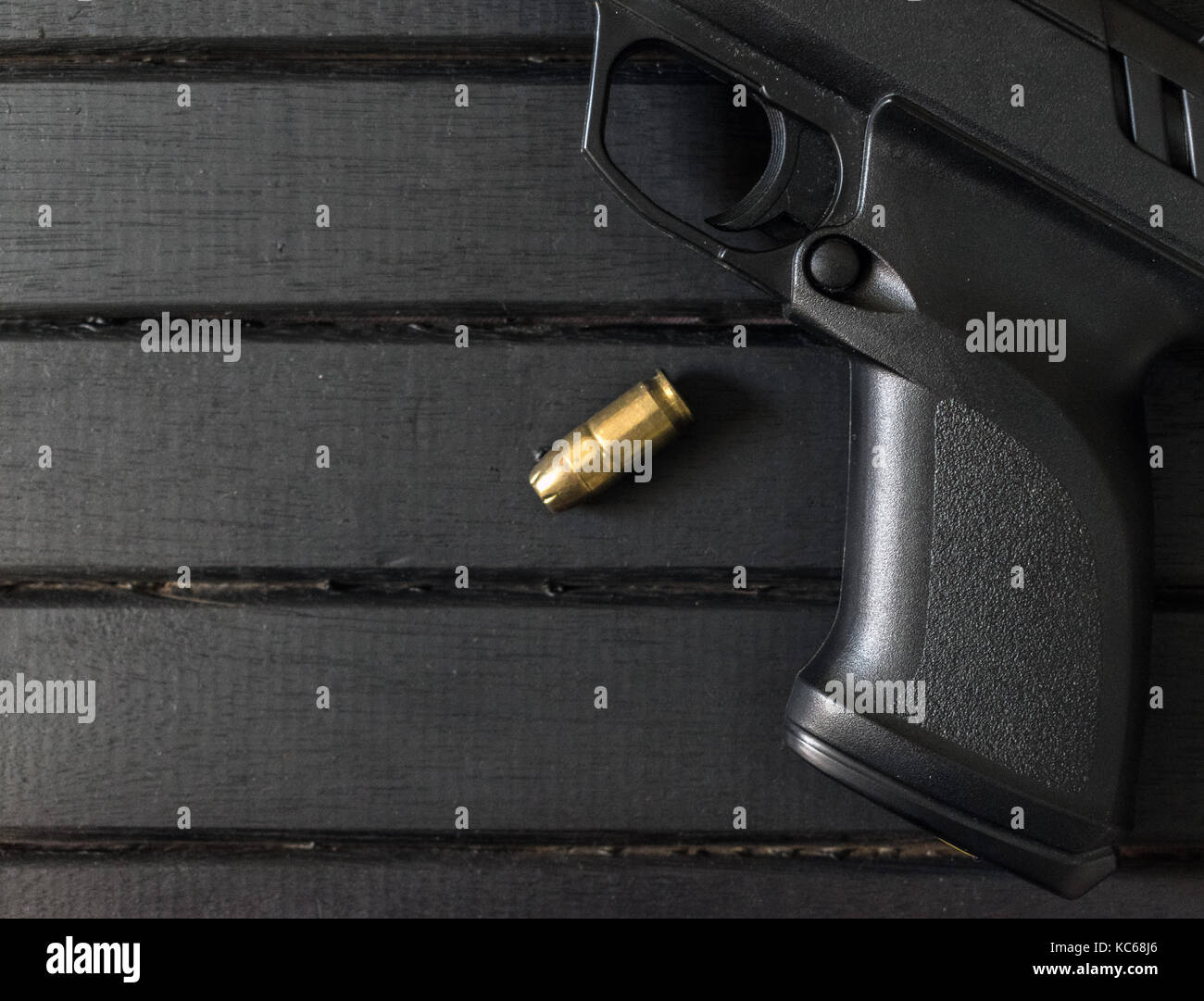 Polymer Pistole und .45 Kaliber Runde auf einem schwarzen Holz- Oberfläche, Nahaufnahme, Trigger und Strukturierte Grifffläche Stockfoto
