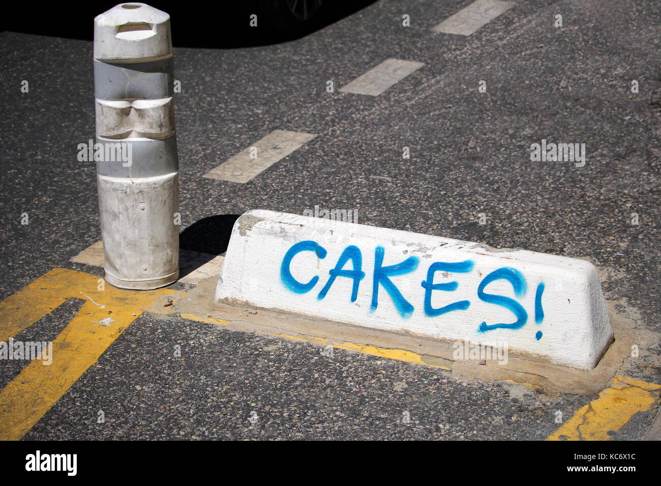 Traffic Control Poller und Betonklotz mit dem Wort "Kuchen!' im Sprühfarbe geschrieben Stockfoto