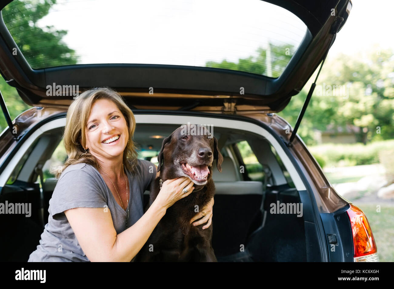 Portrait von Frau streicheln Labrador Retriever im Kofferraum Stockfoto