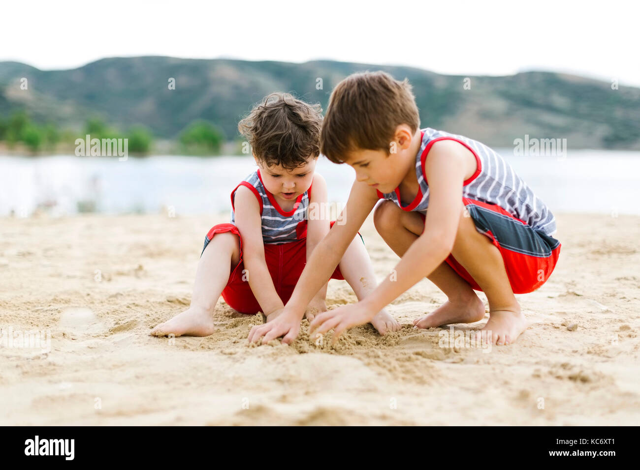 Brüder (4-5, 6-7) spielen am Strand von See Stockfoto