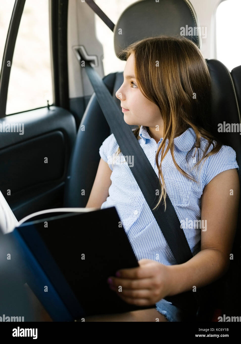 Mädchen (8-9) sitzen im Auto und schauen durch das Fenster Stockfoto