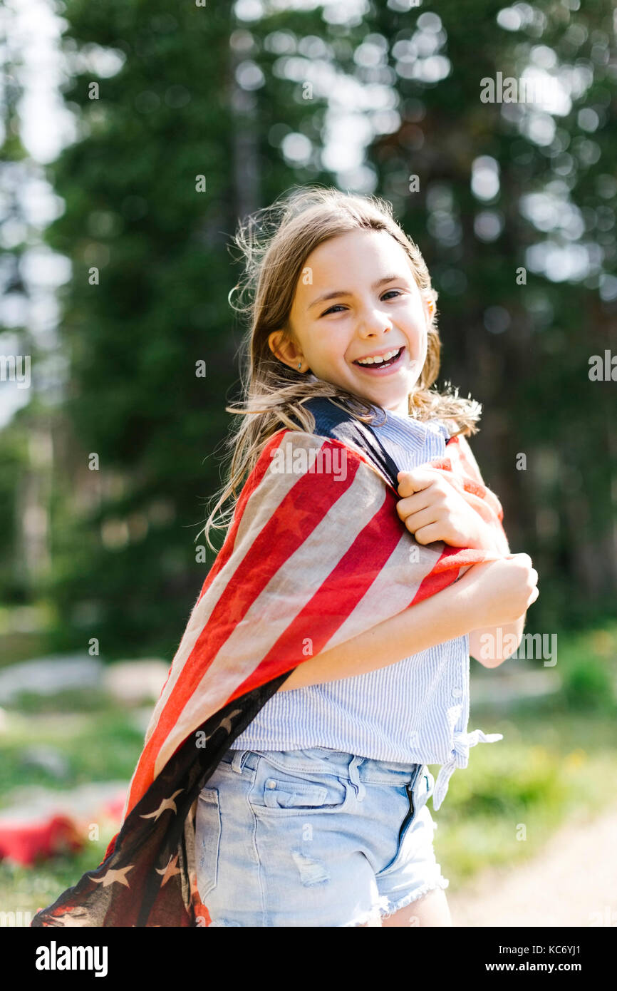 Portrait von Mädchen (8-9) in us flag Wrapped in Wald Stockfoto