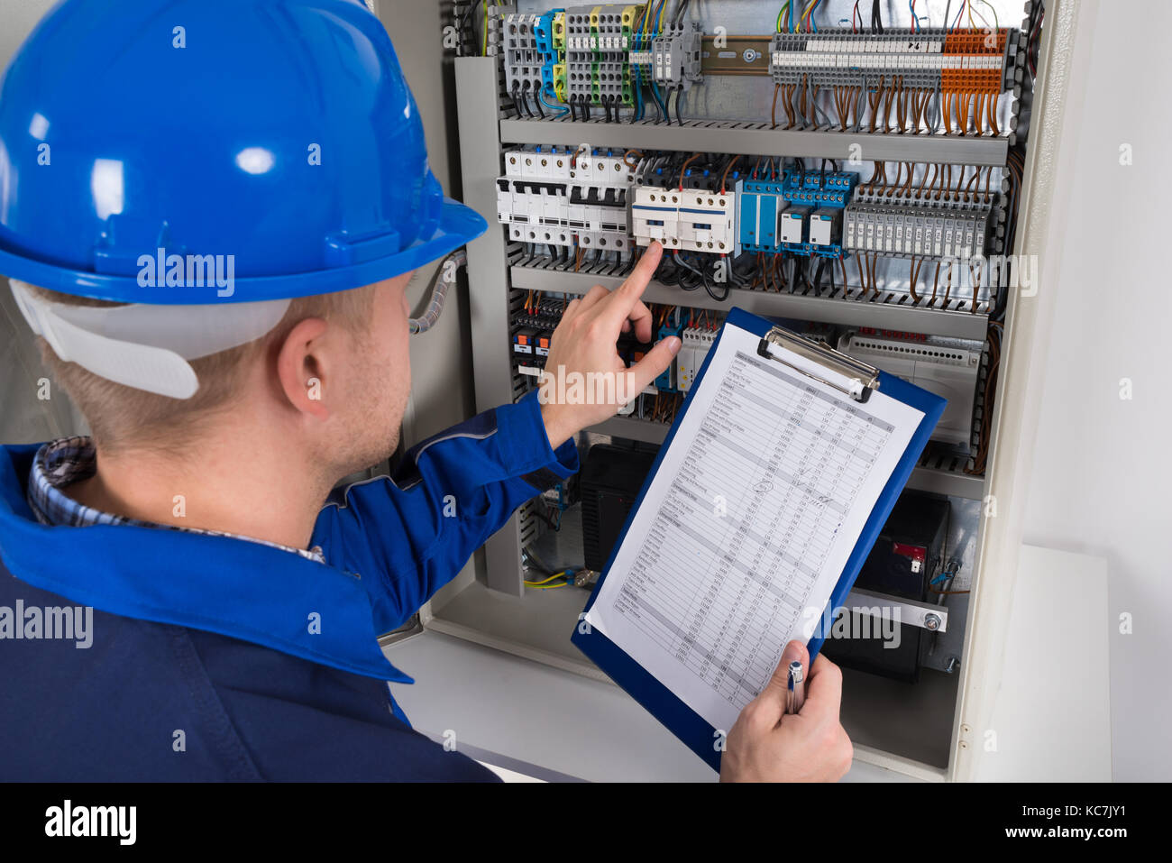 Junge männliche Techniker Holding Zwischenablage während der Prüfung Sicherungskasten Stockfoto