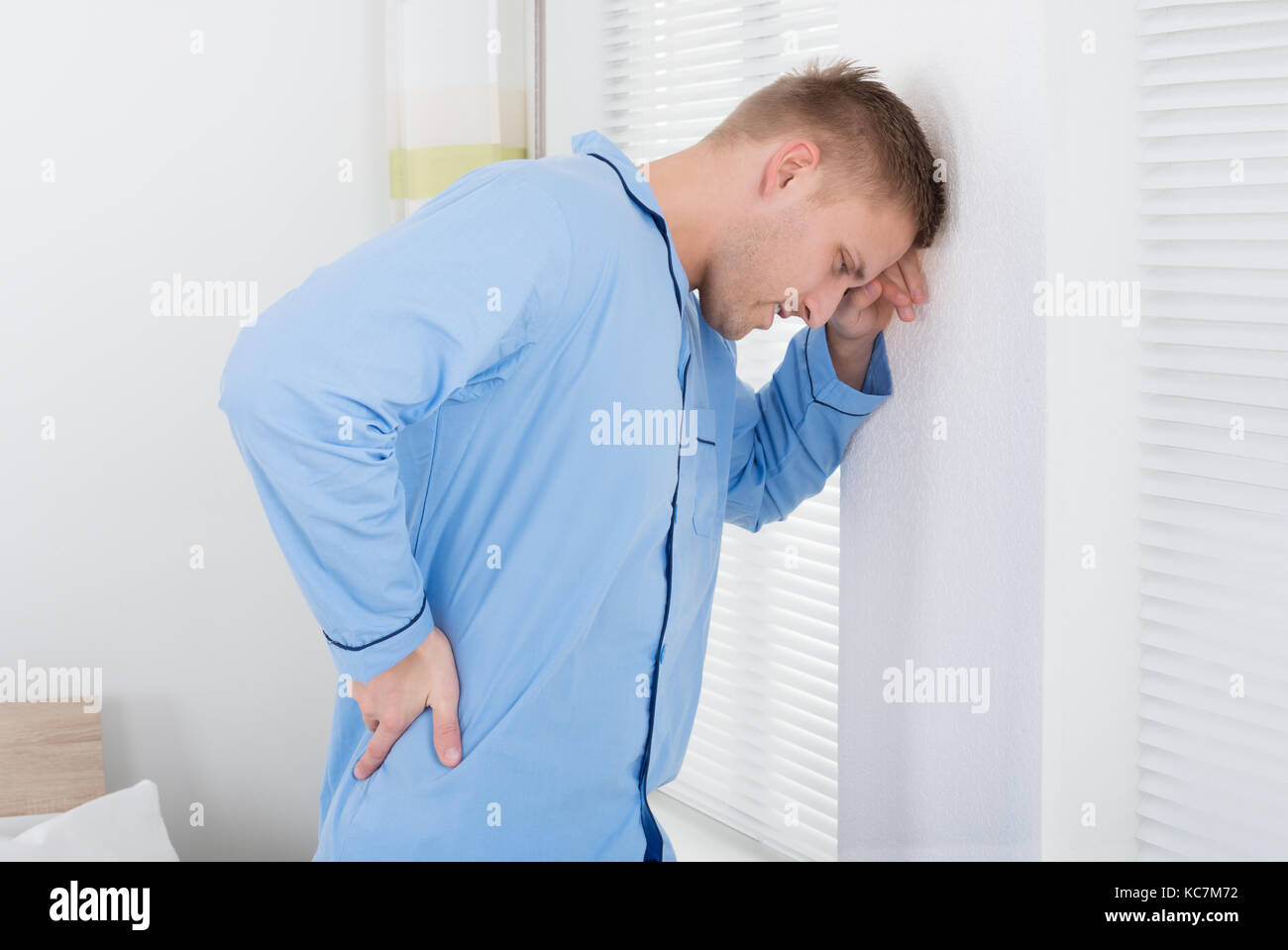 Menschen leiden unter Rückenschmerzen, gegen Wand Stockfoto