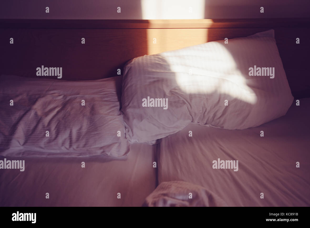 Unordentliche Bett in den Morgen, weiß kissen im Schlafzimmer mit Sonnenlicht Stockfoto