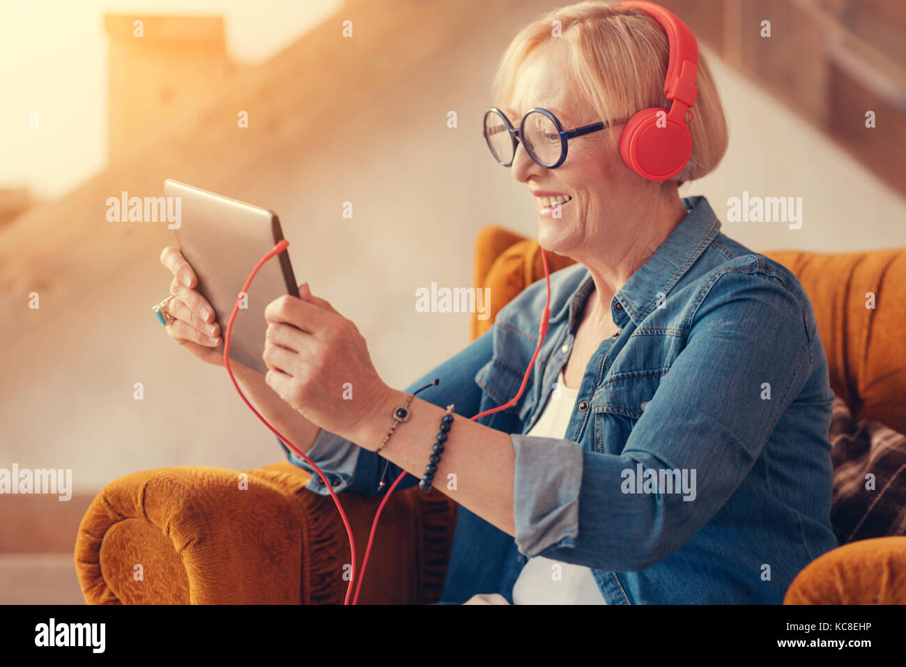 Freudige gealterte Frau mit der Tablette zu Hause Stockfoto