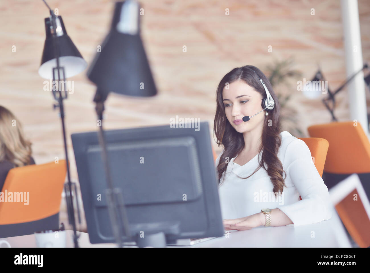 Junge Frau arbeiten im Call Center, von den Kolleginnen und Kollegen umgeben Stockfoto