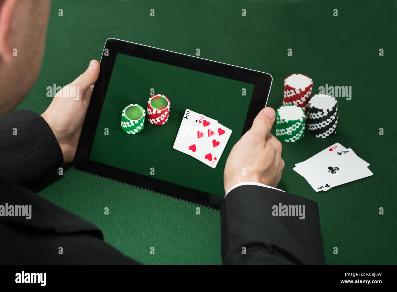 Nahaufnahme einer Poker Hand mit digitalen Tablet mit Chips und Karten Stockfoto