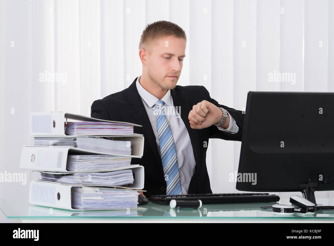 Junge Unternehmer mit Blick auf seine Uhr im Büro Stockfoto