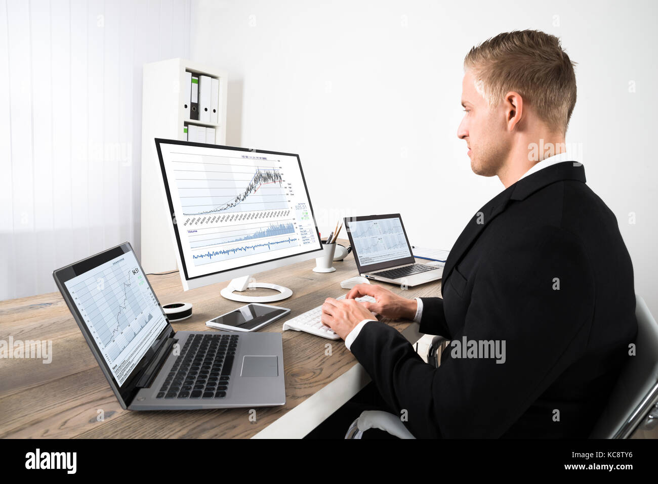 Junge Börse Broker in den Diagrammen auf den Computer im Büro suchen Stockfoto