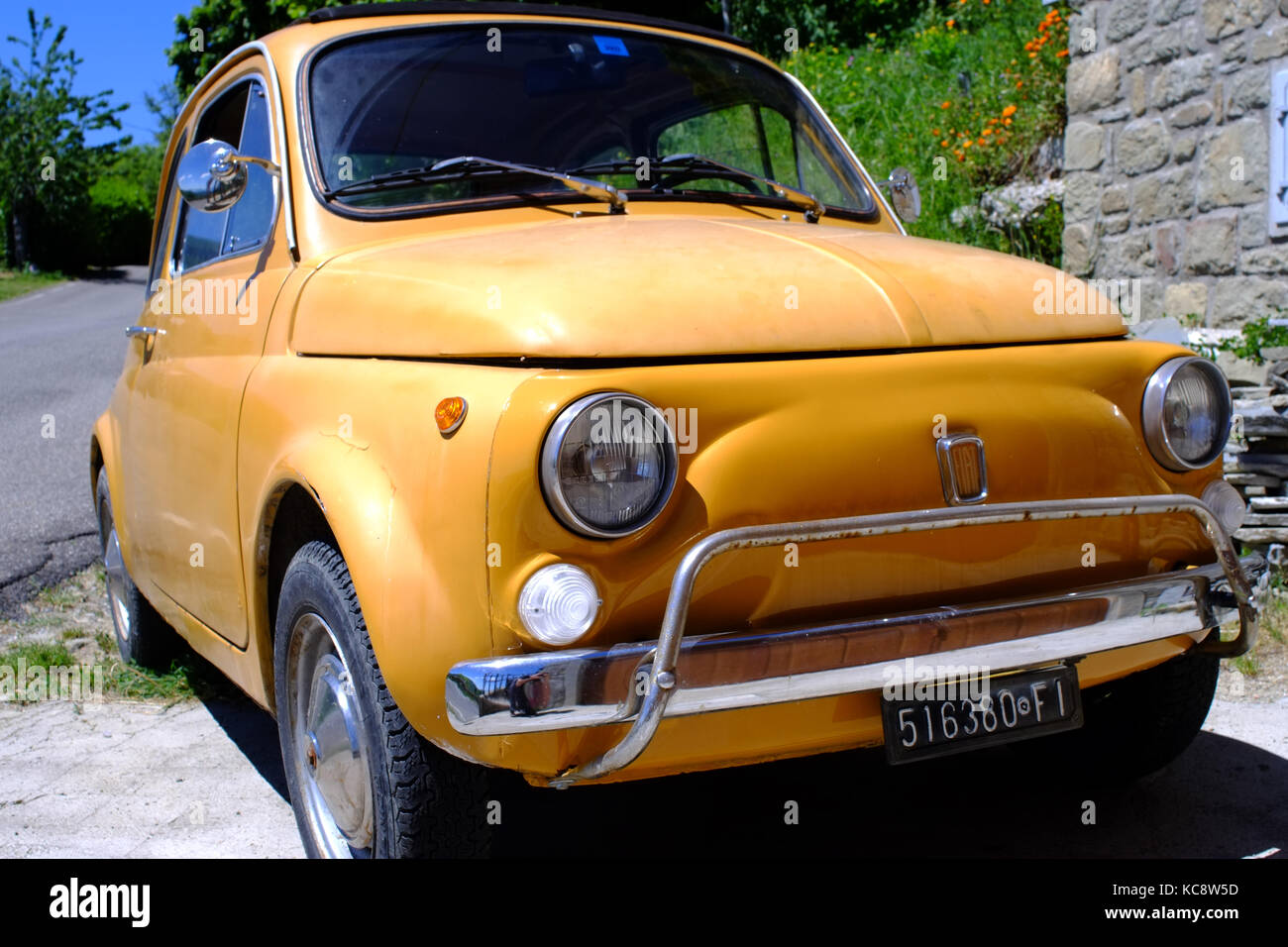 Gelbe Fiat 500 auf dem Land neben einem Stein Haus geparkt. Classic vintage Modell. Die Hügel der Toskana, Italien Stockfoto
