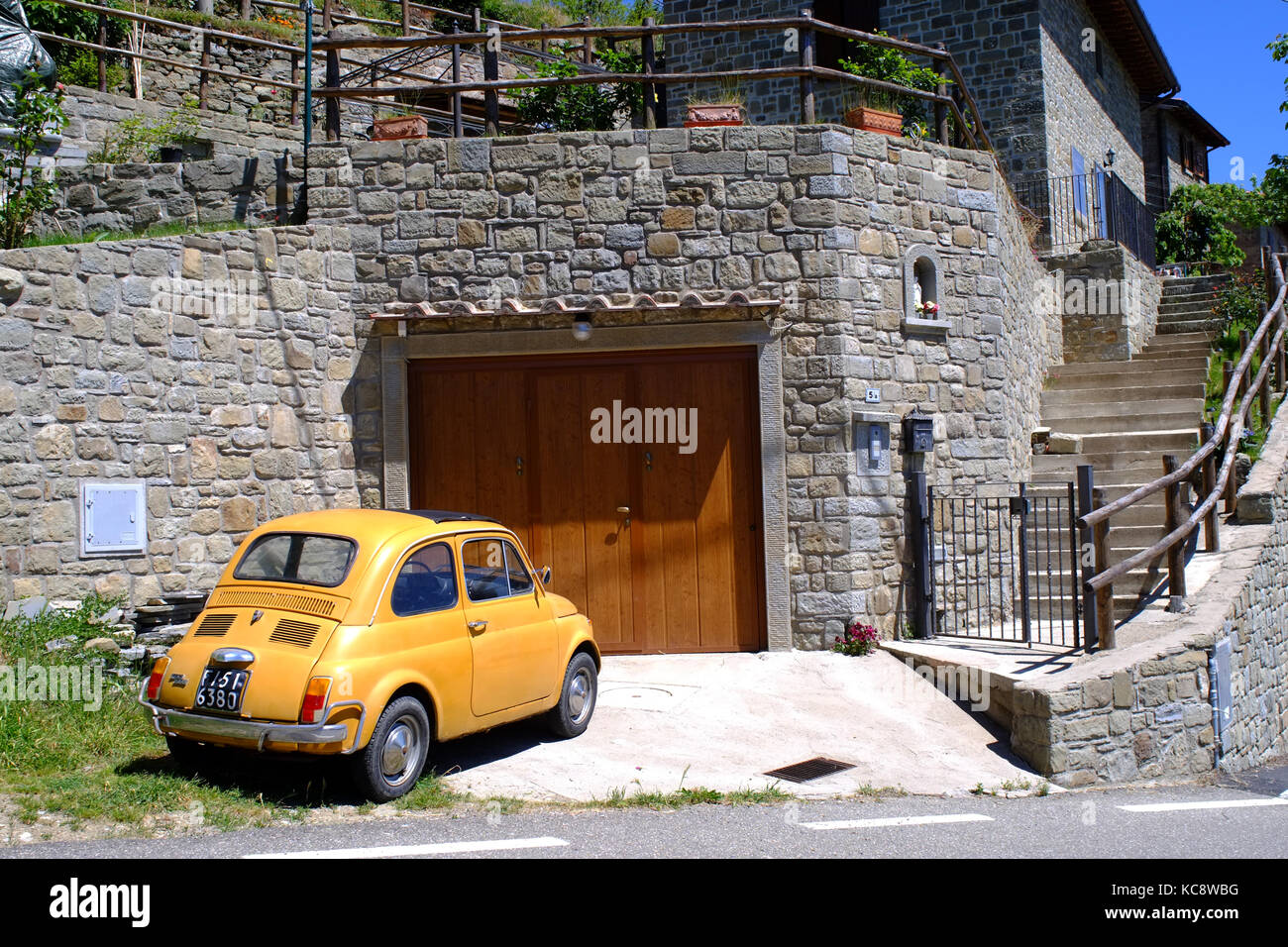 Gelbe Fiat 500 auf dem Land neben einem Stein Haus geparkt. Classic vintage Modell. Die Hügel der Toskana, Italien Stockfoto
