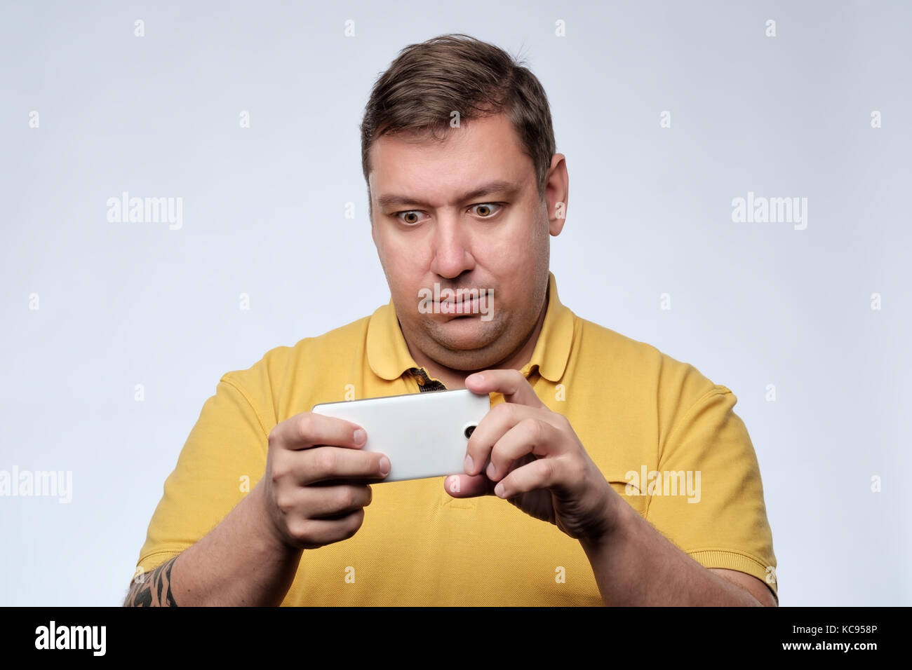 Ein Porträt von überrascht junge fetter Mann mit Handy. Stockfoto