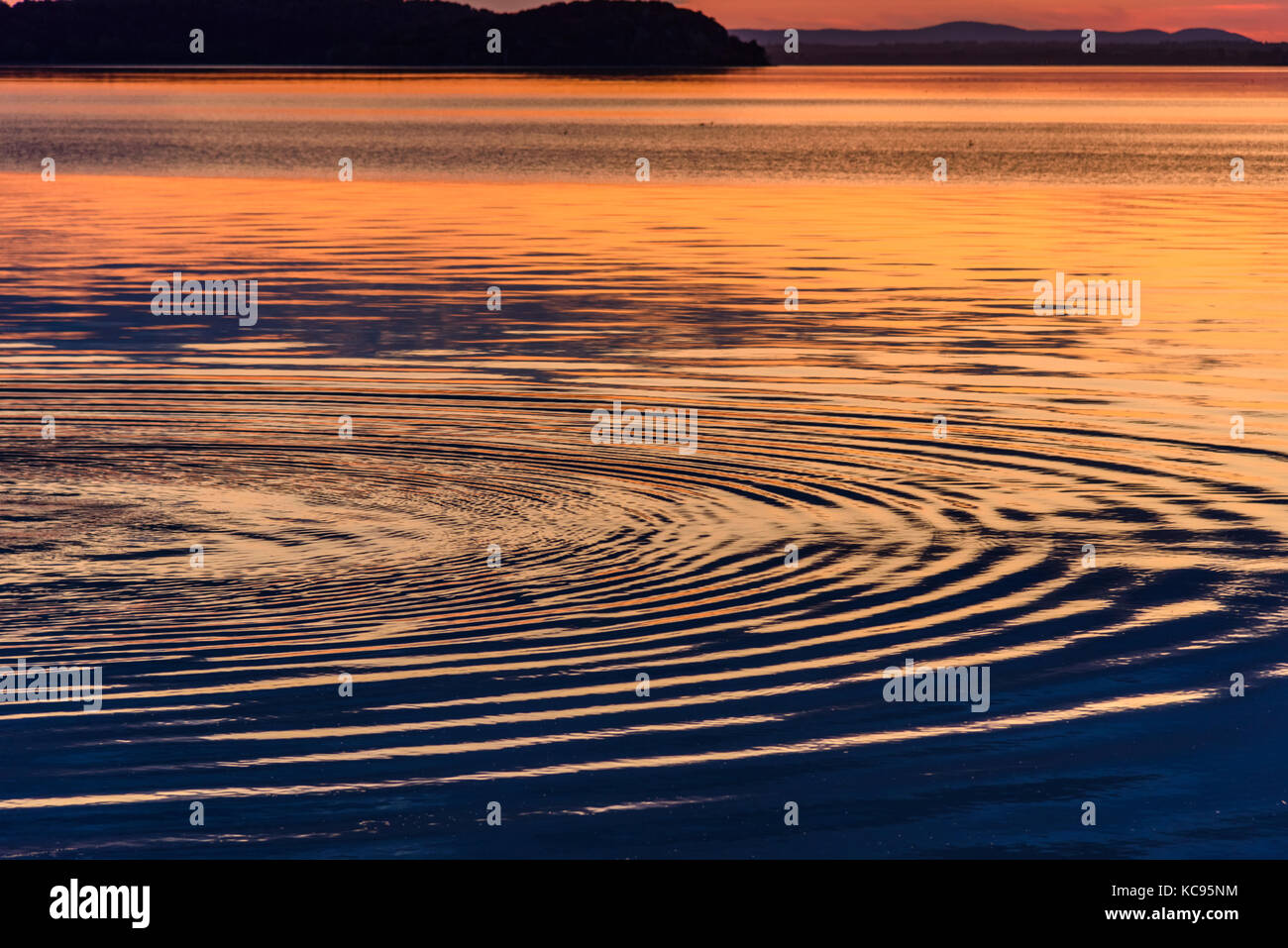 Konzentrische Kreise im Wasser eines Sees bei Sonnenuntergang Stockfoto