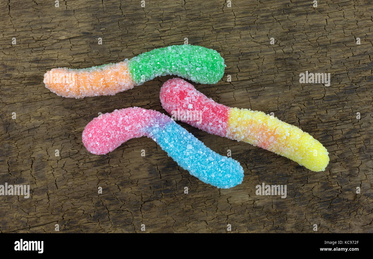Blick von oben auf die drei Zucker überzogen Sauer schmeckende bunte Gummibärchen Worms auf einem alten Braun. Stockfoto