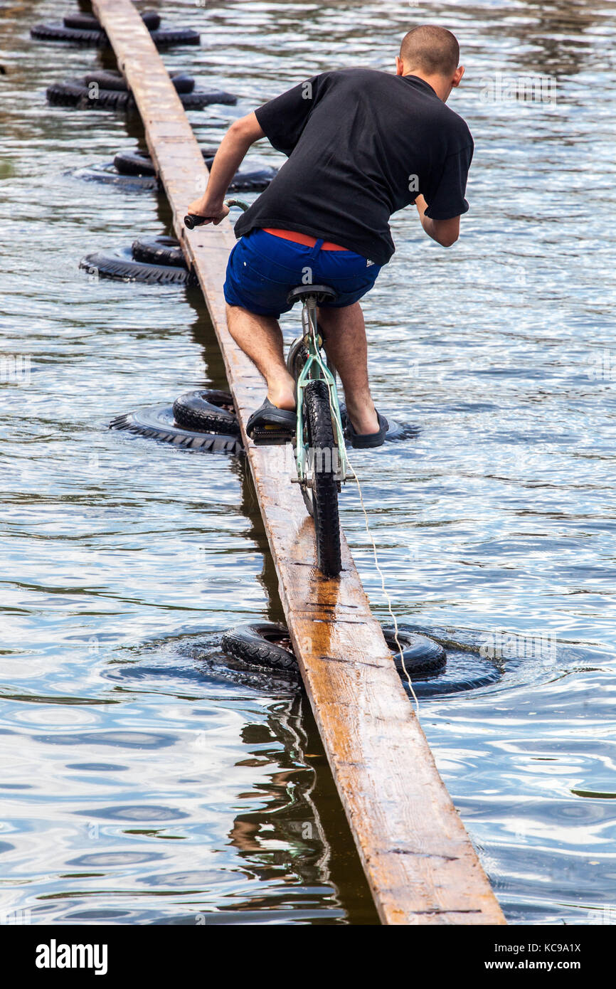 Beim tschechischen Festival versucht EIN Radfahrer auf einer Holzfußbrücke, den Teich zu überqueren, den Ganzjährigen Wettbewerb in einem kleinen Dorf Blazkov, Tschechien Stockfoto