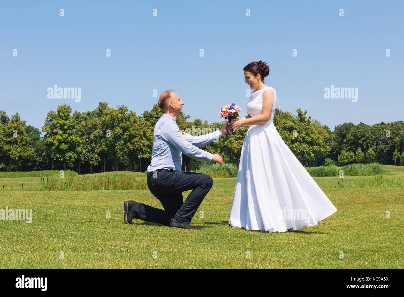 Man macht einen Vorschlag zu seiner Freundin zu heiraten. Heiratsantrag. Liebe und Ehe Konzept. Junge attraktive fröhliche Paare, die in den Park. Stockfoto