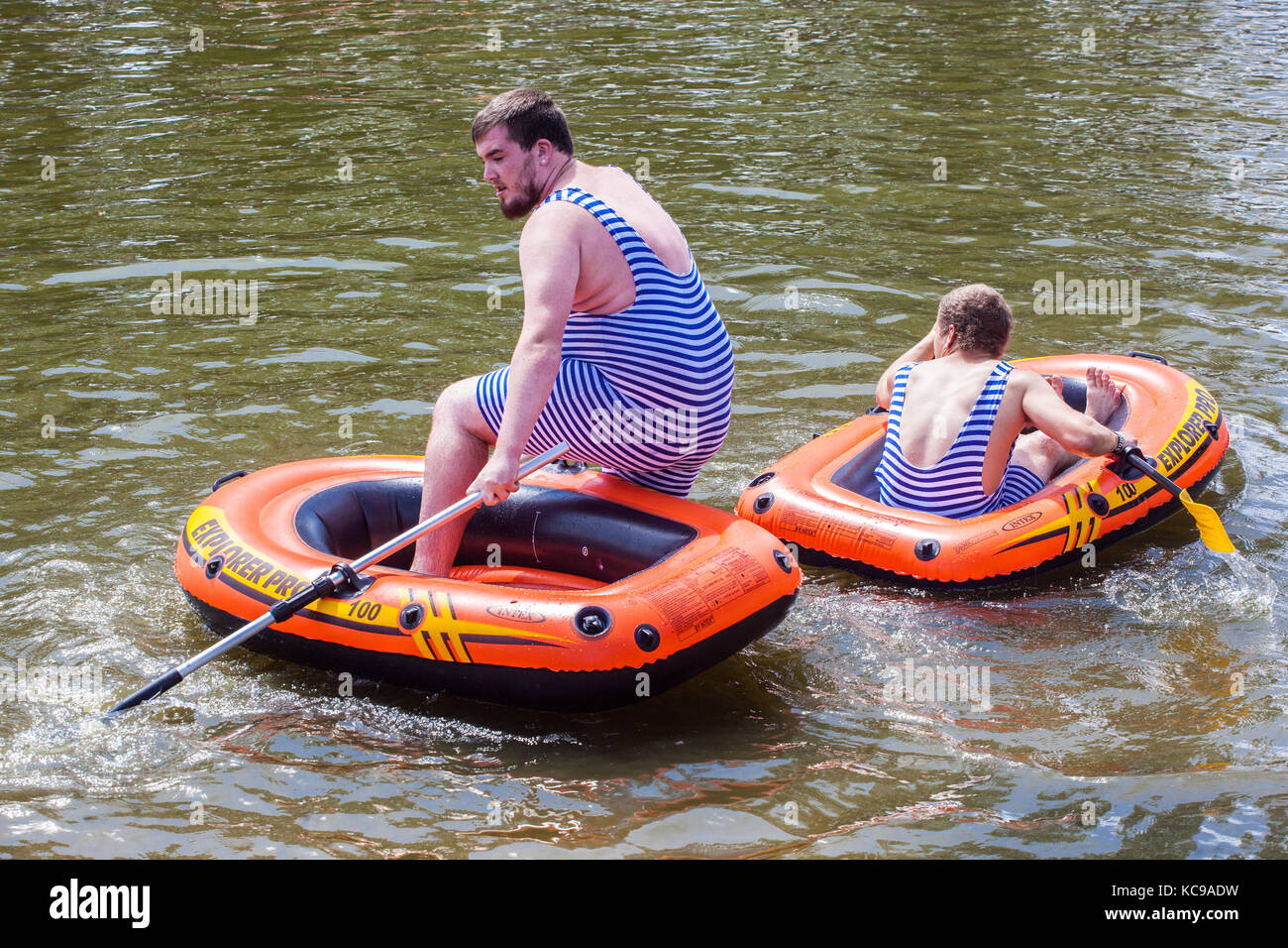 Zwei Männer in aufblasbaren Booten in gestreiften Badeanzügen, Sommerspaß auf dem Wasser, gestreifter Badeanzug Stockfoto