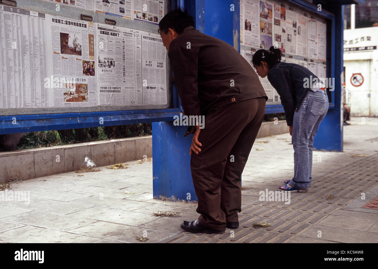 2005, Kunming, Yunnan, Volksrepublik China, Asien - zwei Menschen lesen öffentlich Zeitungen an einem strassenrand in Kunming angezeigt. Stockfoto