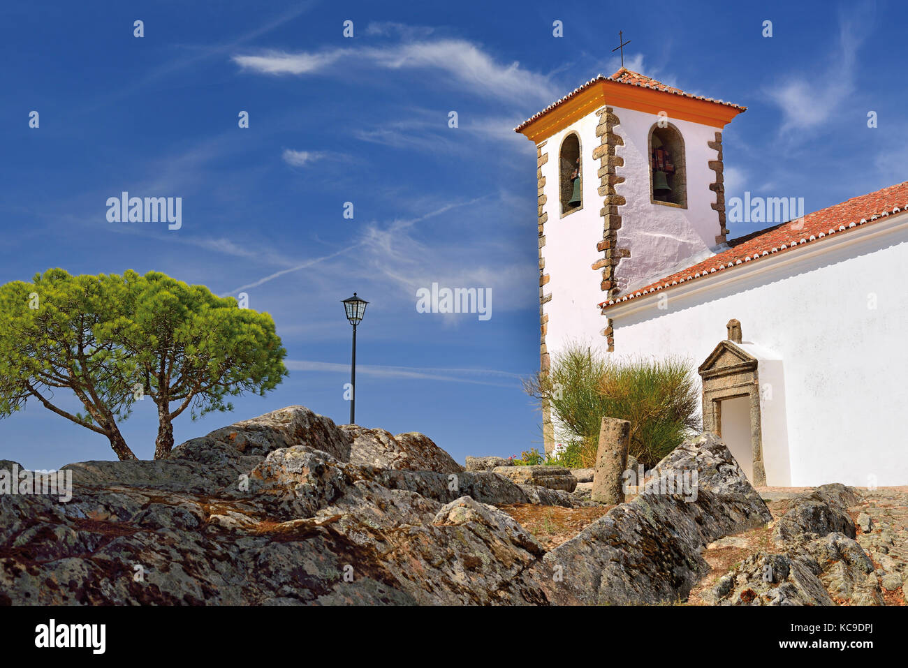 Mittelalterliche weiß gewaschene Kirche mit Felsen, Baum und blauem Himmel Stockfoto