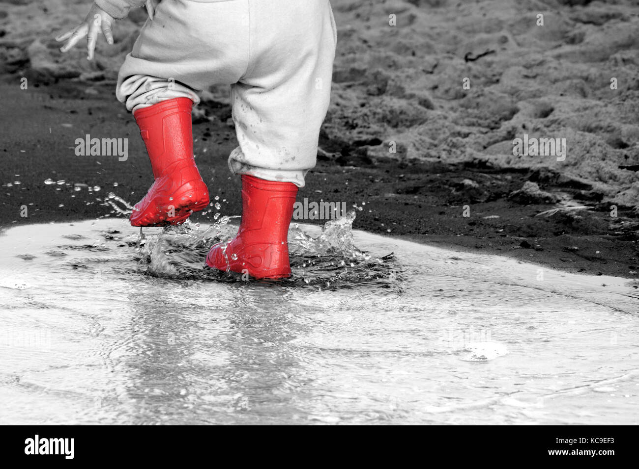 Gummistiefel in der Pfütze. Kid Gummistiefel im Meer Hintergrund Stockfoto