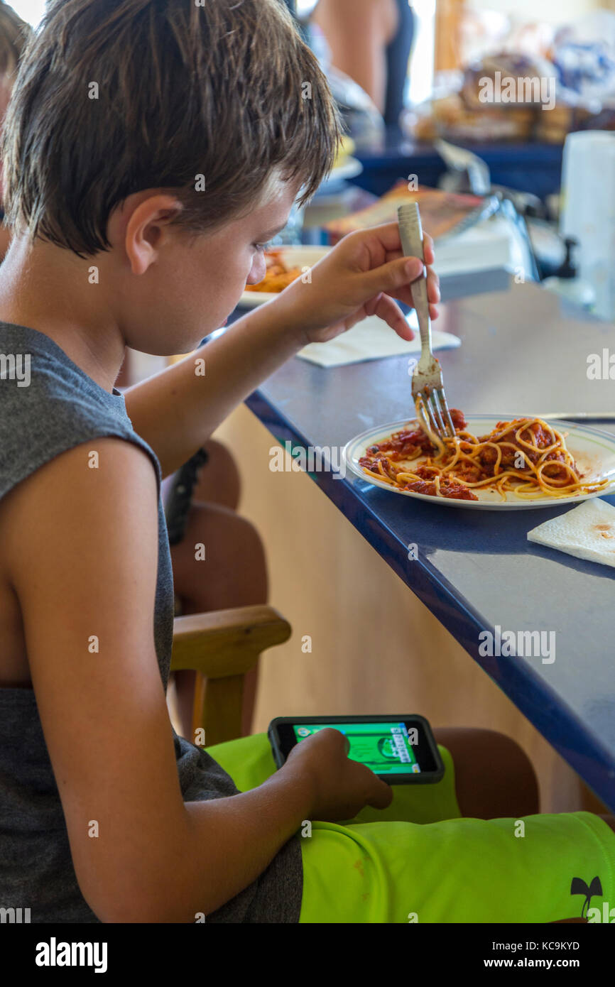 Avon, Outer Banks, North Carolina, USA. Junge Essen beim Spielen mit Mobile Gaming Gerät. Stockfoto