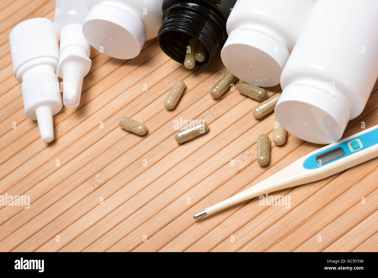 Satz von verschiedenen kalten Hilfsmittel. Öffnen Sie Dunkelgrün jar mit verstreuten Kapseln von weißem Kunststoff Gläser von Arzneimitteln, Nasensprays umgeben, Thermometer Stockfoto