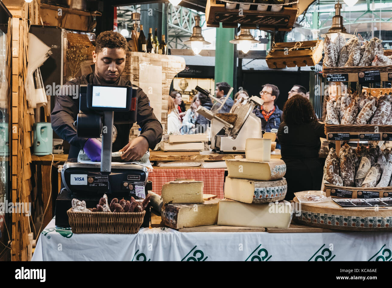 Verkäufer Wiegen und Verpacken von Käse im Deli stand auf der Borough Markt, eines der größten und ältesten Märkte in London. Stockfoto