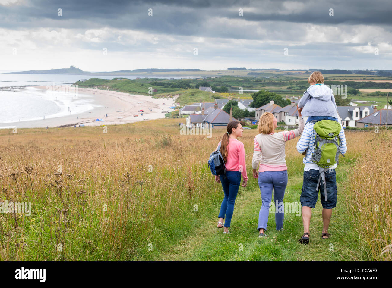 Eine fmaily von vier sind zu Fuß entlang der Dünen. Der kleine Junge ist immer auf seinen Vätern Schultern getragen werden. Stockfoto