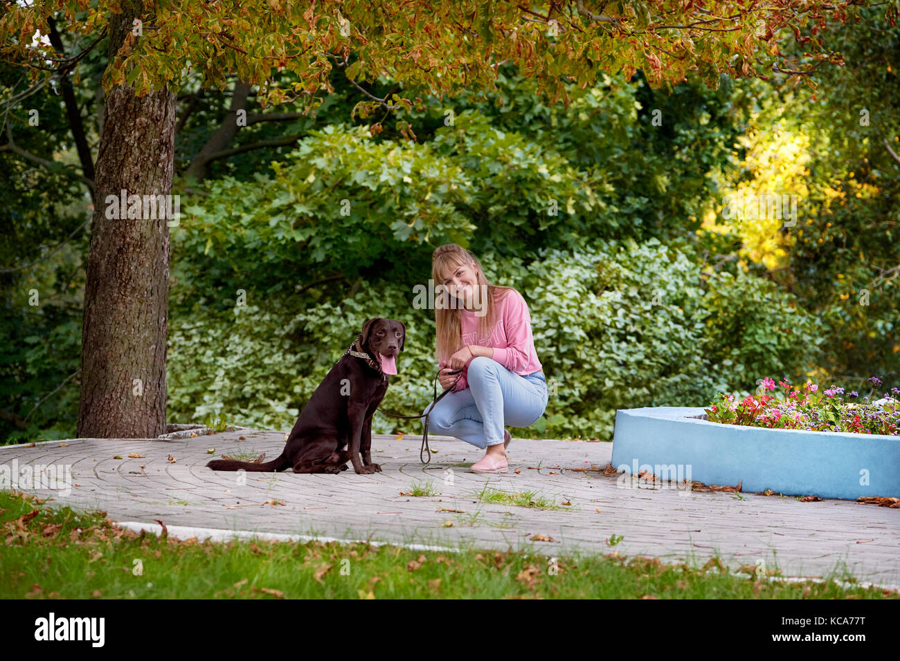 Lächelnde Mädchen mit Hund. Labrador nebeneinander sitzen Stockfoto